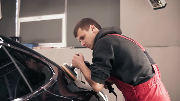 Man in Red Onezie Polishing Black Car alt
