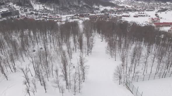 Aerial view of the ski resort with snowy mountain slopes and winter trees.  alt