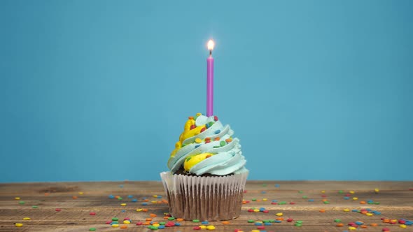 Birthday Cupcake with Candles and Decorations on a Blue Background alt