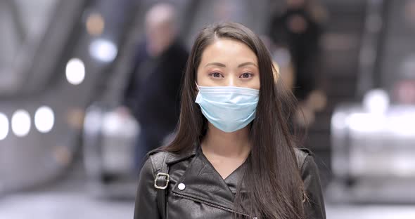 Chinese woman in London wearing face mask to protect from covid 19 coronaviru alt