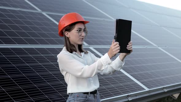 Beautiful young engineer standing near solar panels outdoors, Green Energy Concept. alt