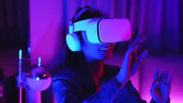 Young asian woman is using virtual reality headset. Neon light studio portrai alt