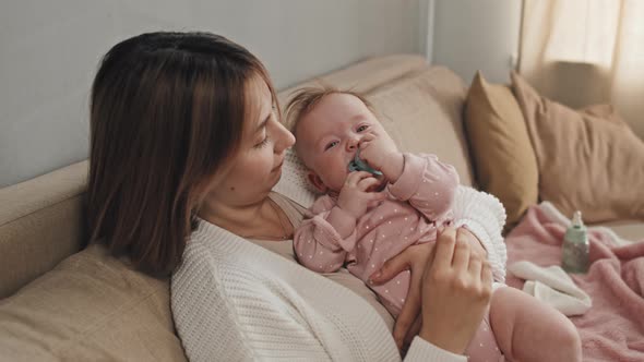 Baby with Pacifier in Arms of Mother alt