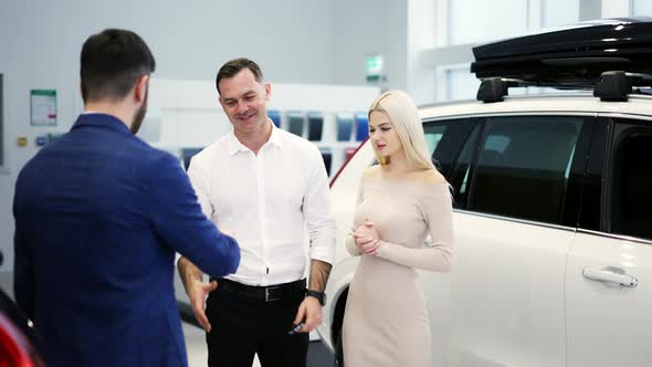 Young Married Couple Take Congratulations From Auto Dealer Hugging Each Other alt