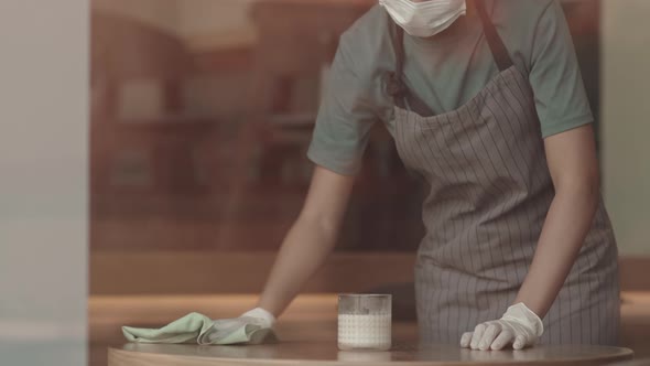 Young Mixed-race Waitress Cleaning Cafe Tables alt