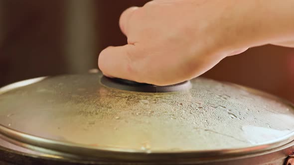 the Caucasian Hand Opens and Closes the Glass Lid From the Skillet with an Omelet with Fresh