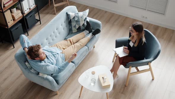 High Angle View of Funny Guy Talking to Psychologist While Woman is Laughing Enjoying Session alt