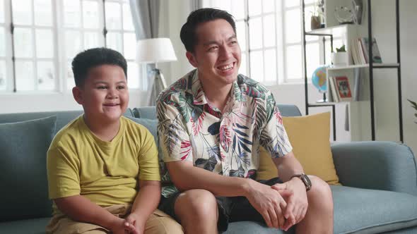 Happy Asian Father And His Son Are Watching Tv While Spending Time Together At Home alt