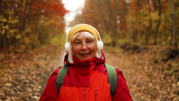 Cheerful Active Mature Happy Woman in Stylish Clothes Walking Along Having Fun Outdoors in City Park alt
