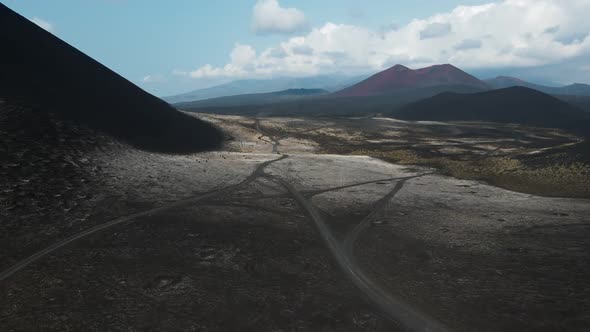 cars drive on black earth overlooking volcanoes