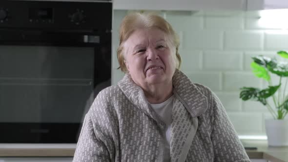 Elderly Woman Laughs and Rejoices at Home in the Kitchen alt