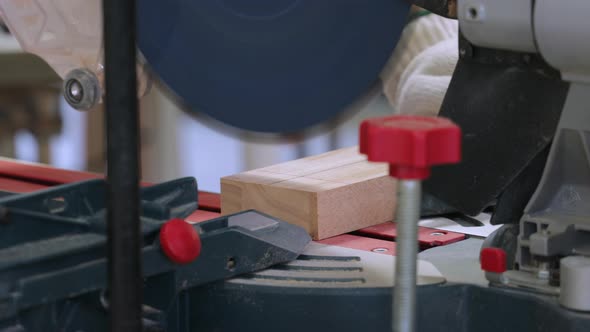 Close-up of carpenter cutting wooden plank with a circular electric saw in carpentry workshop