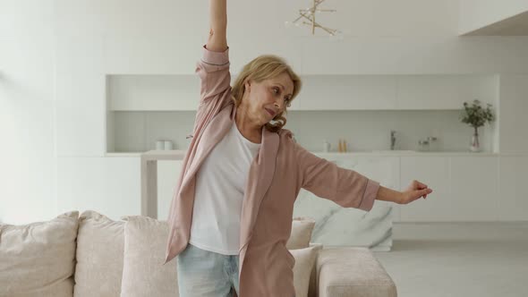 An Active Elderly Woman Doing Pilates at Home Trains in the Living Room alt
