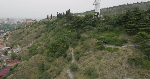 Mysterious and gloomy tilt up drone shot of the Mother of Georgia monument. alt