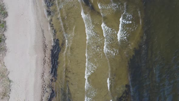 Aerial aerial top view from a drone of a sandy beach with sea waves in autumn.