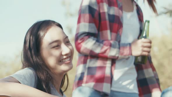 Young Asian woman with friends happy camping in nature having fun together playing guitar.