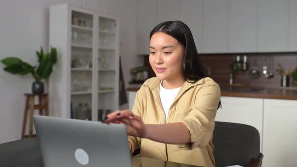 Overjoyed Young Asian Woman Surprised Victory and Looking at the Laptop Sitting at Home
