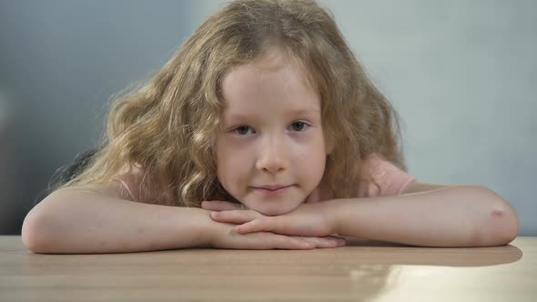 Lonely Little Girl Sitting at the Table and Looking Into Camera, Orphanage alt