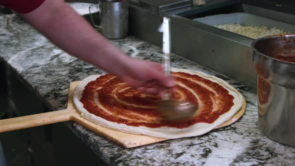 Cheese pizza with sauce being made