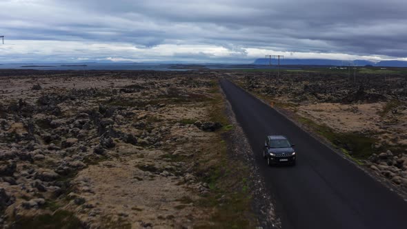 Aerial of Car Driving Along an Empty Asphalt Road In Iceland alt
