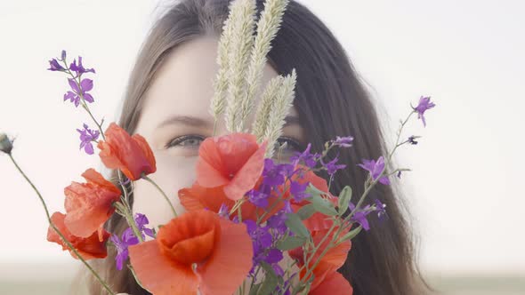 Portrait of a Young Fat Pretty Woman with a Bouquet of Wild Red Poppies with Purple Delphinium and alt