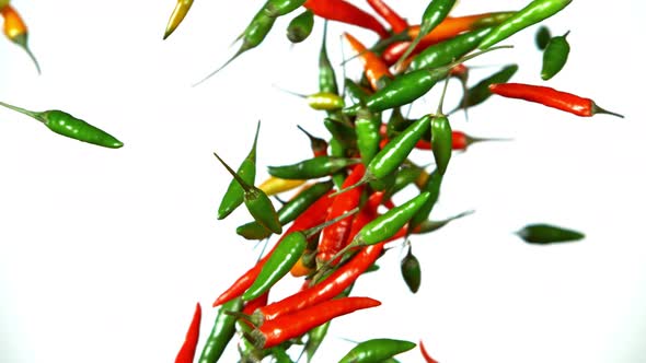 Super Slow Motion Shot of Mixed Chilli Side Colision Isolated on White Background at 1000Fps. alt