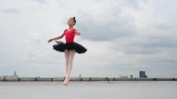 Ballet girl with red dress and black skirt dance on rooftop or terrace of high building in big city alt