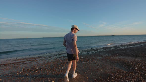 POV Man Collects Plastic Bottle Off of Beach In Slowmotion alt
