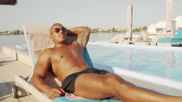 Handsome African Athletic Man Resting Near the Swimming Pool at the Beach