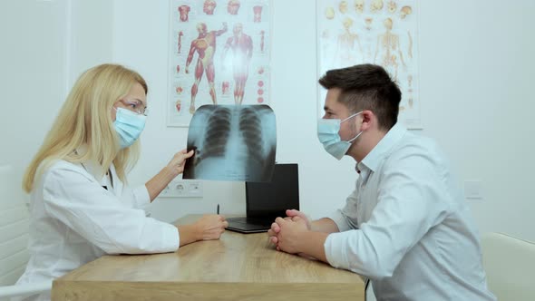 Female Doctor with Glasses in Medical Mask Checking Xray Lungs Consulting a Patient Positive for alt