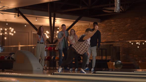 A Young Man Throws a Bowling Ball and Knocks Out a Shot with One Throw and Hugs and Rejoices with alt