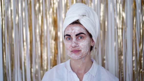 young woman with cosmetic mask on her face and with cosmetic paint on her eyebrows alt