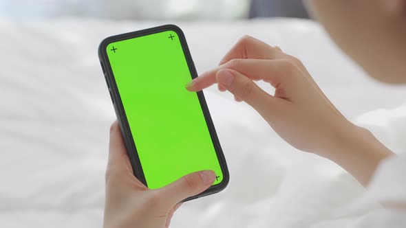 woman holding in hands a mock up smartphone with green screen for internet online. alt