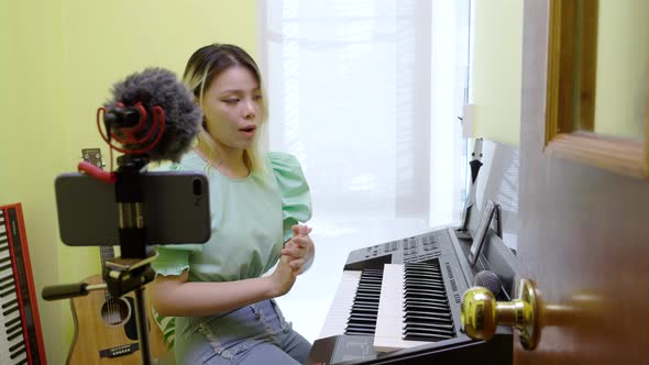 A singing teacher singing and playing piano online and live past her smartphone