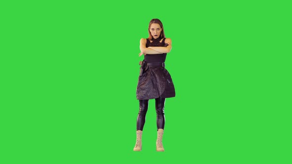 Gamecharacter Girl with a Gun on Belt Stands Folding Her Arms in Threatening Manner on a Green