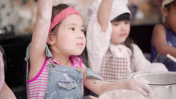 Multi-ethnic young boys and girls happy making dessert cooking in kitchen at school. alt