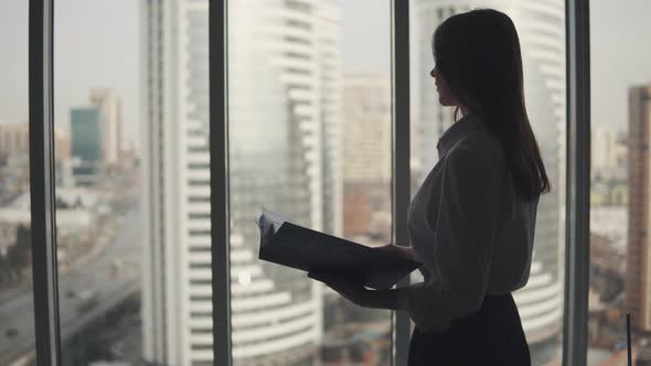 Silhouette of an Attractive Girl with a Folder for Papers in Her Hands alt