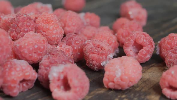 Man Pours Frozen Raspberries on a Wooden Table. Frozen Raspberries Are Poured Onto a Wooden Board alt