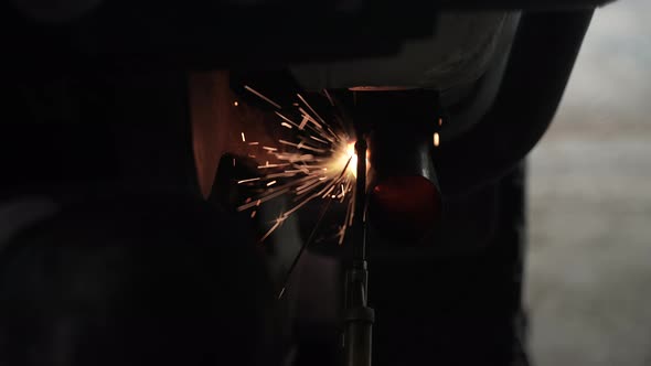 blacksmith welder works with metal steel and iron using a welding machine, bright sparks and flashes alt