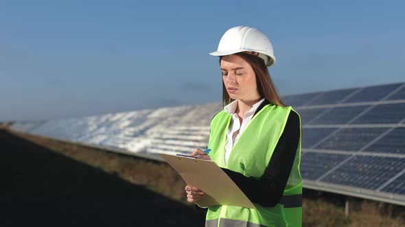 A Female Engineer is Conducting an Inspection of Solar Panels alt