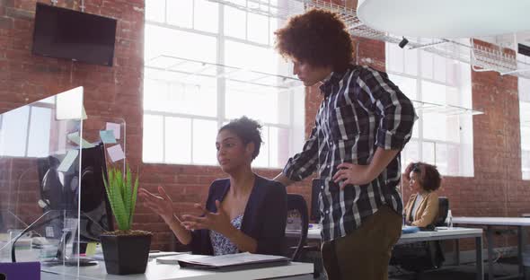 Diverse male and female colleagues discussing over computer screen in office alt