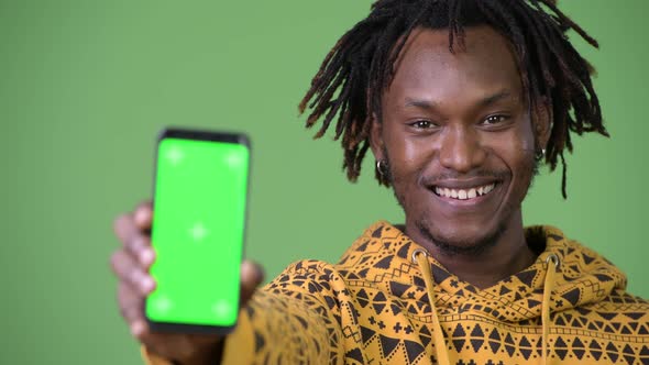 Young Happy Handsome African Man Smiling While Showing Phone alt