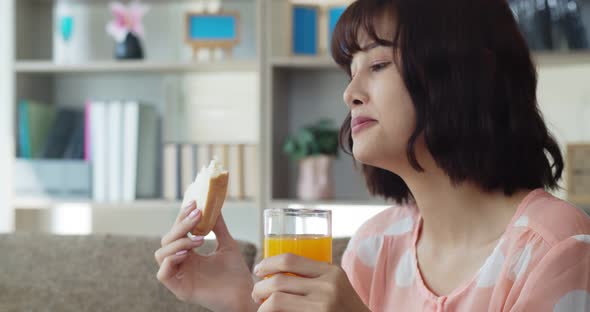 Young pretty woman eating sandwich and orange juice with happy