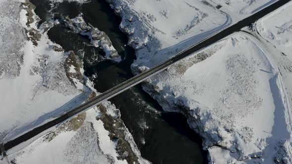Aerial View of the Road Near Godafoss Waterfall, Snowy Shore and River, Iceland in Early Spring