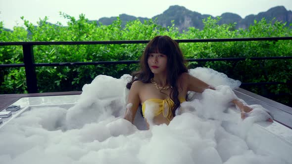 Cute Asian Girl in Bikini in Hot Tube Blowing Soap Bubbles Thailand