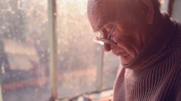 Close Up Elderly Man Glasses Reading Book in House Window