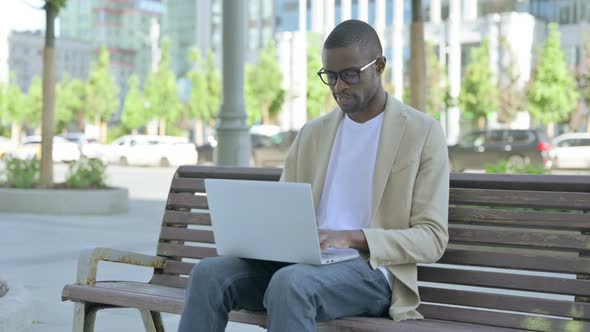Busy African Man Using Laptop Sitting Outdoor on Bench alt