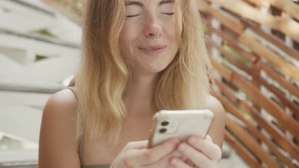A Pretty Young Woman with Vitiligo Pigmentation Sits on the Stairs Chatting on the Phone alt