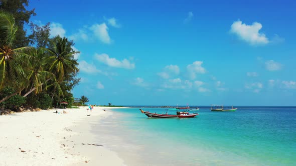 Tropical island beach background. White sand, boats, and palms leaning over the coast. alt