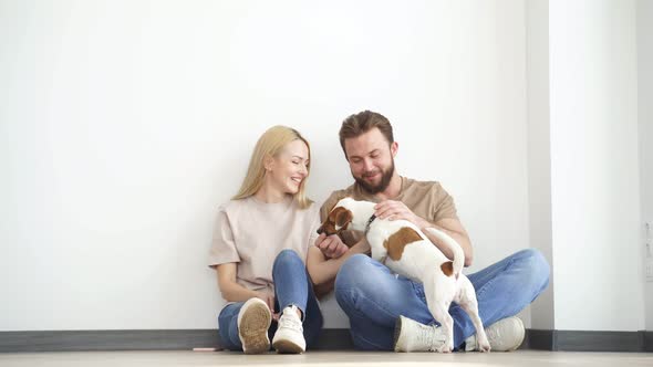Happy Caucasian Couple Family Sit on Floor Playing with Pet Dog Have Fun Enjoy Weekends